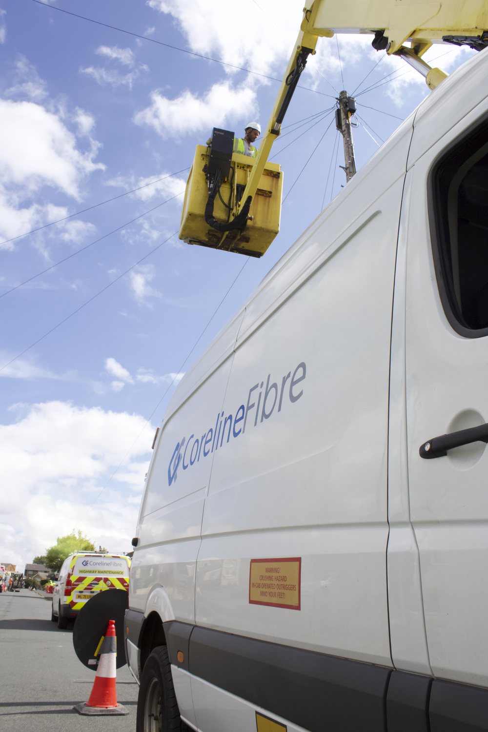 Coreline Fibre engineer working from a MEWP cherry-picker basket on overhead lines beside a branded Coreline Fibre van