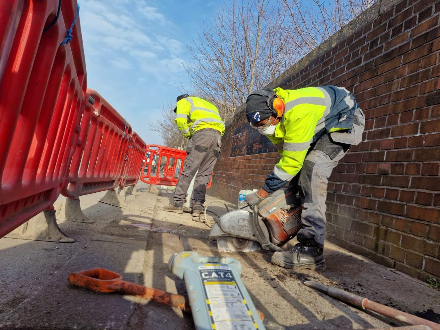 Coreline Fibre engineers carrying out intrusive surveying and footway civils work, using a CAT4 cable detector and cut-off saw
